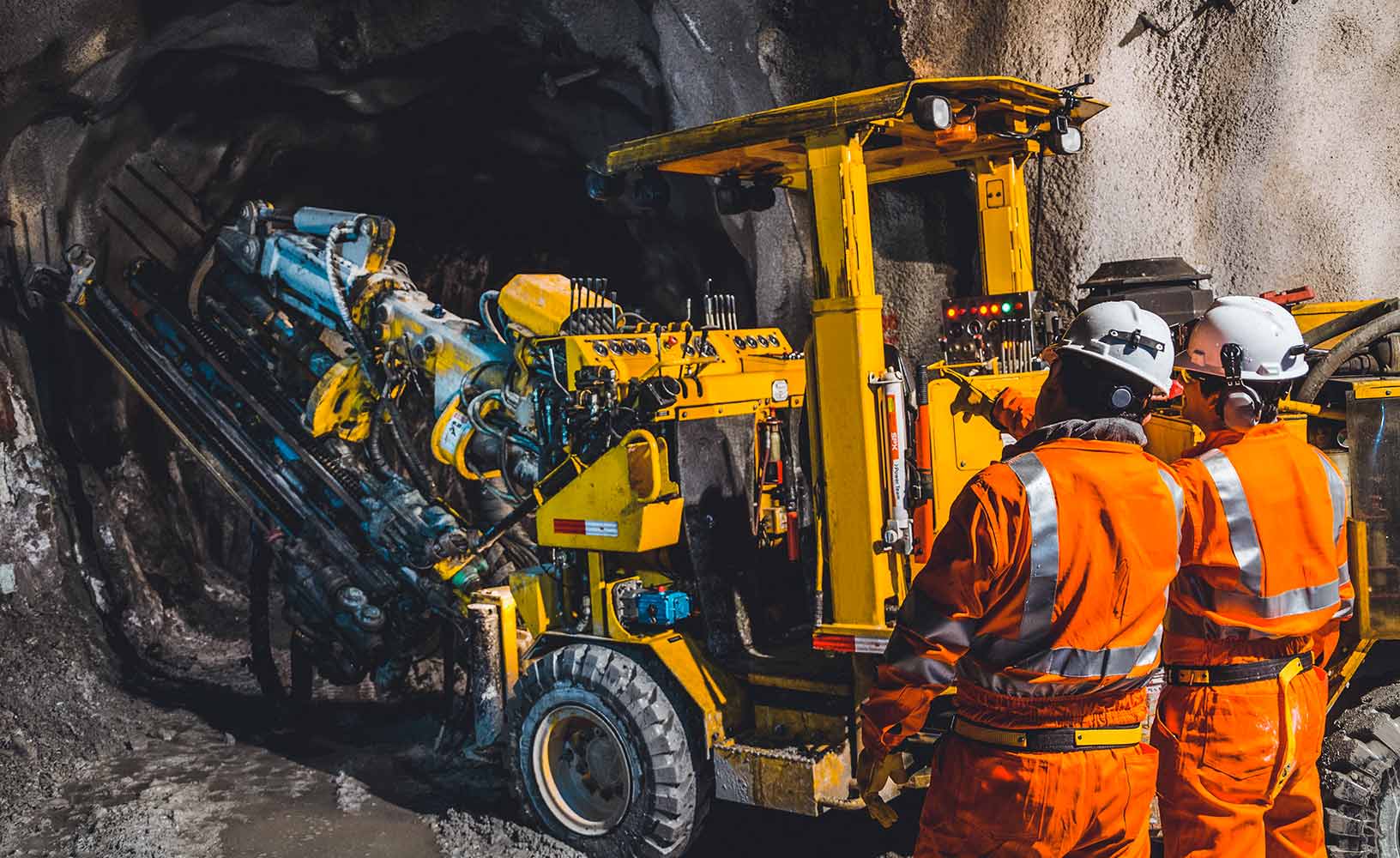 Due minatori sottoterra, davanti a una macchina di estrazione mineraria